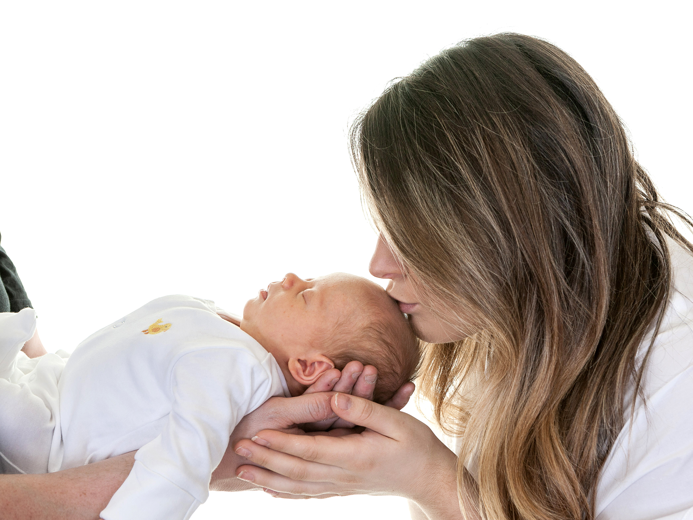 mother kissing her newborn baby on the head while they sleep