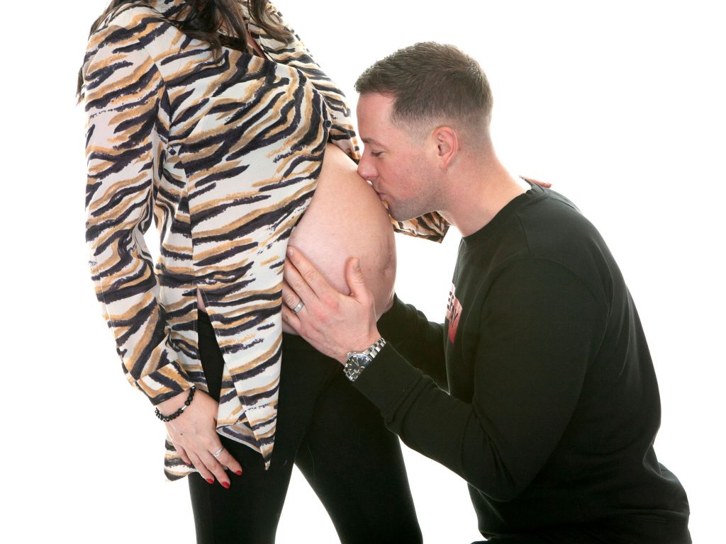father kissing mother to be's stomach